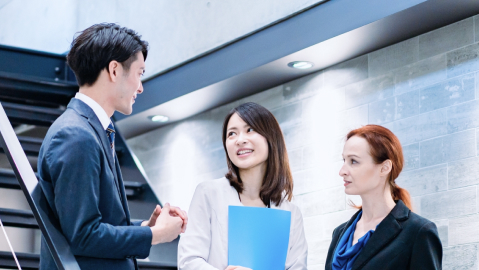 3人の男女がオフィス内で話している様子
